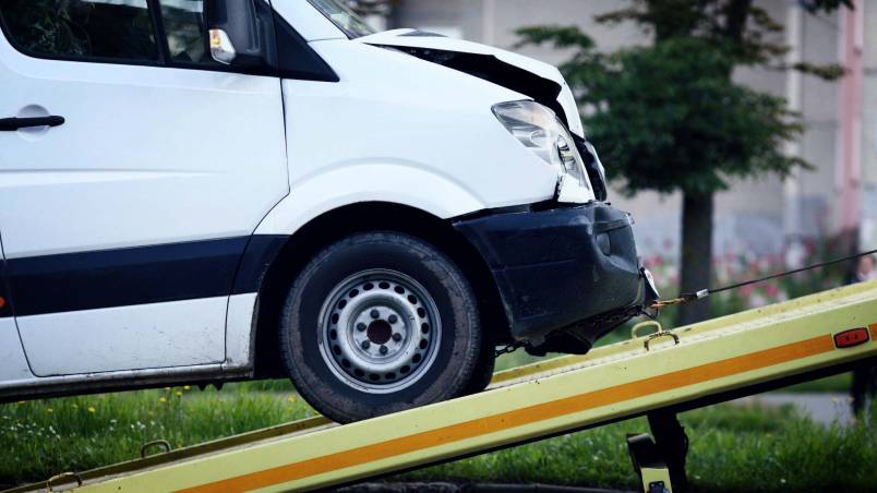 Das Bild zeigt einen weißen Transporter mit beschädigter Front, der auf ein Abschleppfahrzeug geladen wird.
